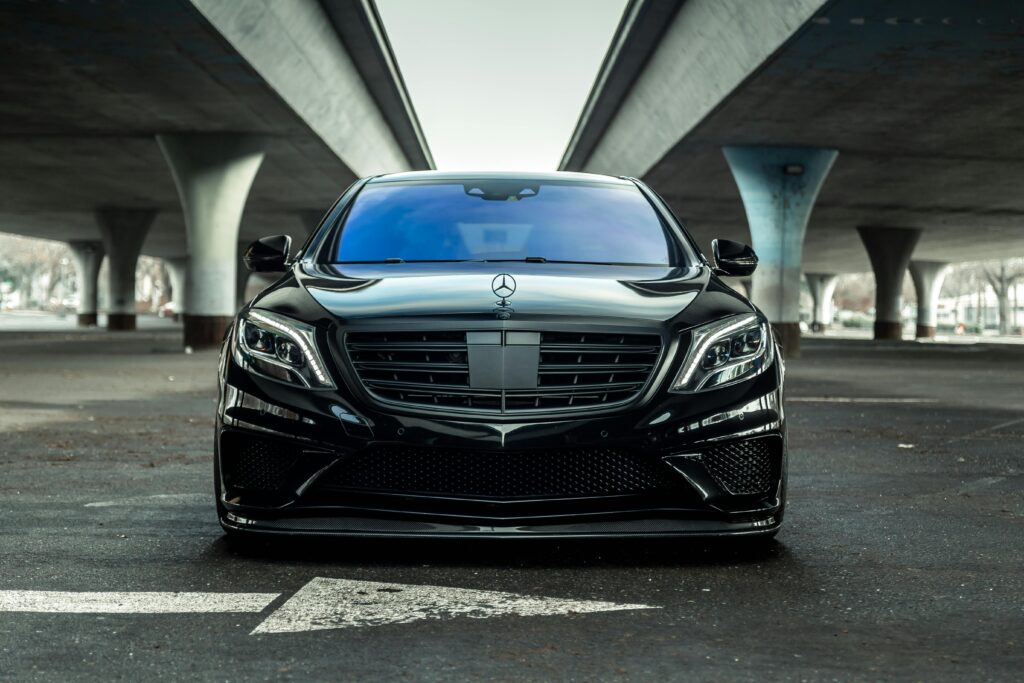 Sleek black luxury car parked outdoors under a modern urban bridge in Sacramento.